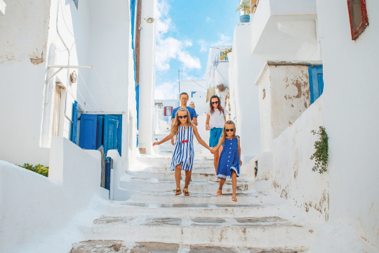 Zwei Kinder laufen vor ihren Eltern eine Treppe in einem griechischen Dort hinunter